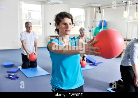 Giovane donna prendendo parte a una classe di pilates. Foto Stock