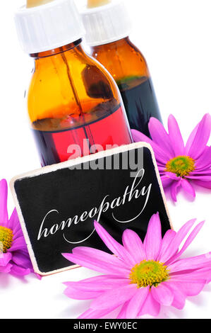 Alcuni flaconi a contagocce e una lavagna con la parola omeopatia scritto su di esso e fiori di colore rosa Foto Stock