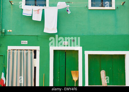 Spazzole di spazzamento una bandiera italiana e linea di lavaggio al di fuori di un dipinto di verde Casa Burano Laguna di Venezia Veneto Italia Europa Foto Stock