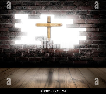 Croce di legno dietro la rottura di un muro di mattoni con luce bianca in background. Foto Stock