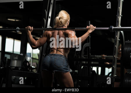 Femmina facendo culturista peso pesante Esercizio per Gambe Barbell Squat Foto Stock