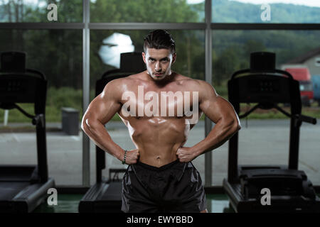 Grave culturista uomo in piedi la palestra e i muscoli di flessione Foto Stock