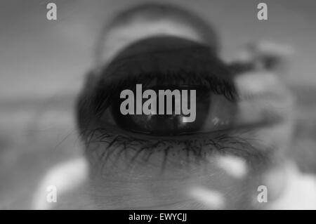 Fotografi 'occhio' immagine concettuale.versione BW.Eye riflesso sulla superficie di vetro mostra fotografo premendo il pulsante di scatto. Foto Stock