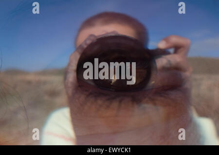 Fotografi 'occhio' immagine concettuale. Occhio riflessa sulla superficie di vetro mostra fotografo premendo il pulsante di scatto. Foto Stock