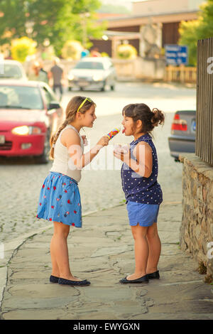 Due ragazze la condivisione di gelati in strada Foto Stock