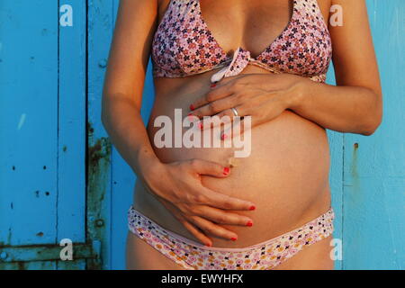 Donna incinta cullano il suo stomaco Foto Stock