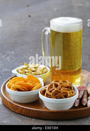 Diversi snack salati e un bicchiere di birra fresca, rustico still life Foto Stock