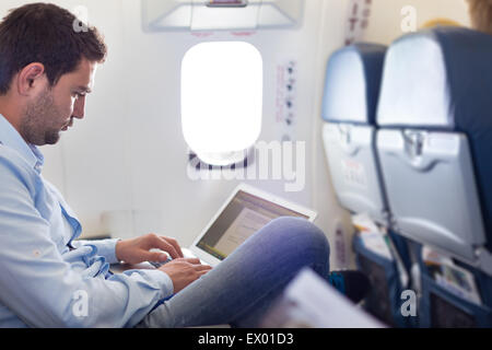Imprenditore lavora con laptop in aereo. Foto Stock