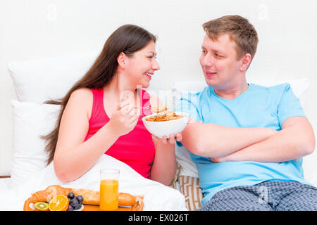 Felice coppia giovane avente la colazione a letto insieme Foto Stock