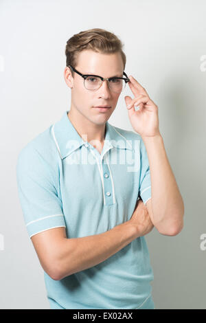 Un bel giovane uomo che indossa 50s occhiali e vintage top, posa con e guardando lontano Foto Stock