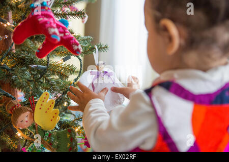 Bambina guardando angel ornamento su albero di Natale Foto Stock