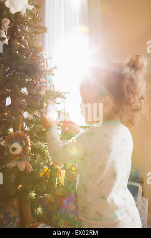 Bambina ammirando Ornamenti natale su albero Foto Stock