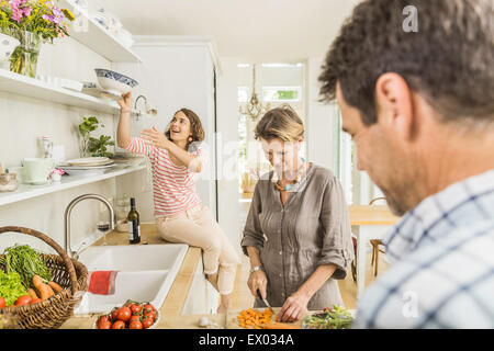 Tre adulti preparare verdure fresche in cucina Foto Stock