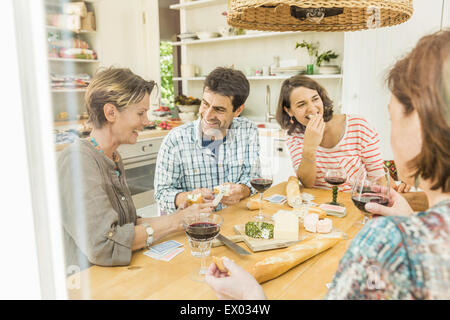 Amici adulti di bere vino rosso e giocando a carte al tavolo da pranzo Foto Stock