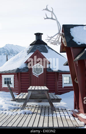 Tradizionale casa in legno e banco di picnic nella neve, Longyearbyen, Svalbard, Norvegia Foto Stock