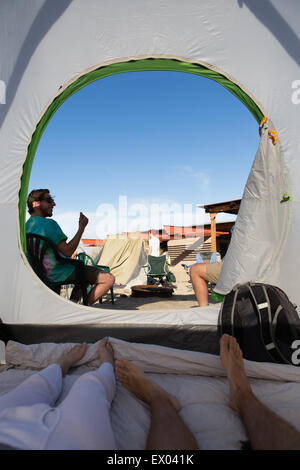 Giovani amici adulti dentro e fuori la tenda, Anza-Borrego Desert State Park, California, Stati Uniti d'America Foto Stock