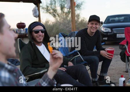 Tre giovani amici di sesso maschile seduto a chattare su campeggio, Anza-Borrego Desert State Park, California, Stati Uniti d'America Foto Stock