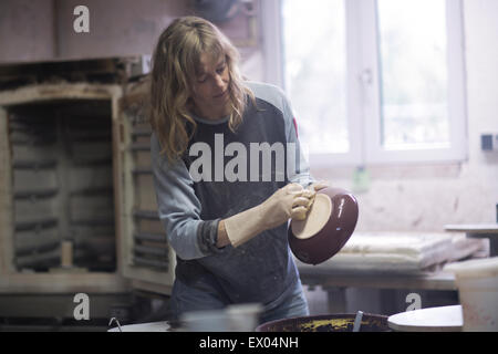 Potter femmina controllo bordo del recipiente smaltato in officina Foto Stock