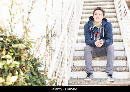 Giovane uomo seduto sui gradini Foto Stock