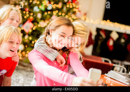 Ragazza adolescente e fratelli tenendo selfie sullo smartphone a natale Foto Stock