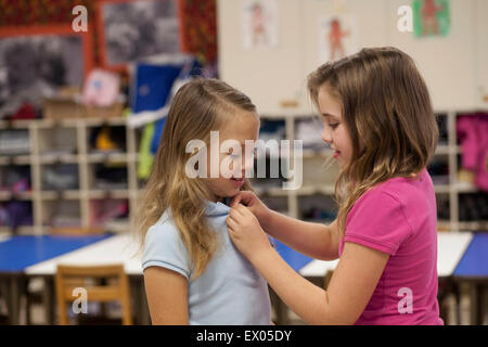 Ragazza abbottonatura amico della tee shirt in aula Foto Stock