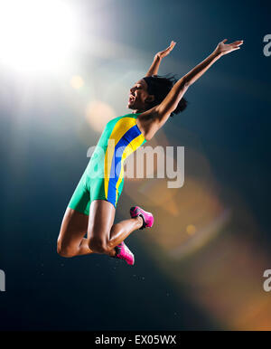 Giovane atleta femminile saltando metà aria nella celebrazione in stadium Foto Stock