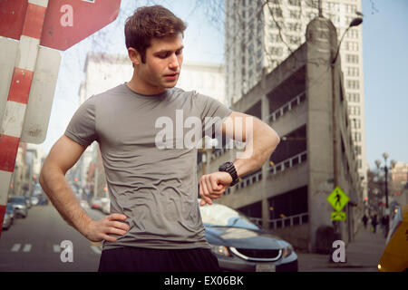 Giovane maschio runner controllo orologio da polso, Pioneer Square, Seattle, Stati Uniti d'America Foto Stock