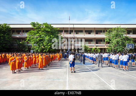 Giovani monaci e scolari riuniti per gruppo di mattina in una scuola adiacente al Wat Phra Singh, Chiang Mai Foto Stock