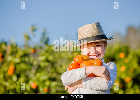 Sorridente ragazzo sano per gli agrumi azienda agricola le arance nelle sue mani Foto Stock