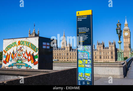 LONDON, Regno Unito - 30 giugno 2015: una vista di un souvenir di Londra chiosco, un cartello stradale e il Palazzo di Westminster a Londra, il 30 Giu Foto Stock