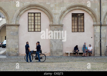 Anziane Signore seduto su una panchina e due uomini parlare. Foto Stock