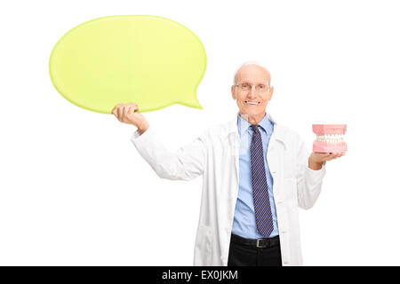 Coppia dentista in camice bianco tenendo una dentiera e un grande giallo discorso bolla isolati su sfondo bianco Foto Stock