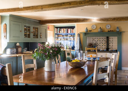 Legno di ciliegio agriturismo tabella in stile country la cucina con pavimento lastricato e travi a soffitto Foto Stock