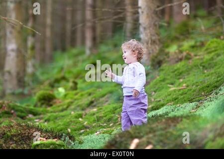 Happy Laughing baby girl giocando in una splendida pineta in autunno Foto Stock