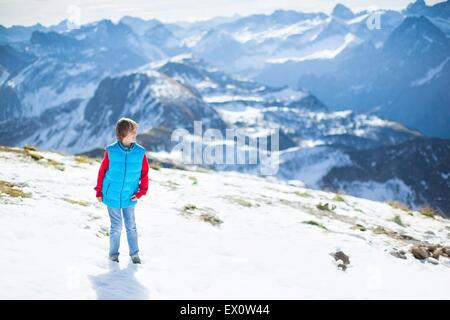 Ridendo felice ragazzo giocare nella neve sulla sommità di una splendida montagna delle Alpi Foto Stock