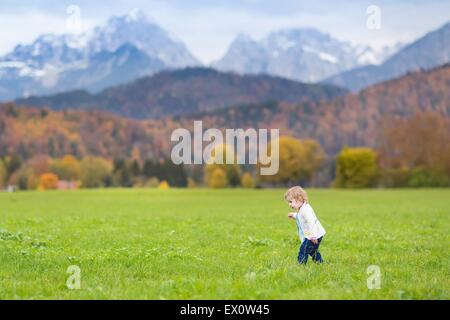 Carino bambina in esecuzione in un bellissimo campo in le Alpi in autunno Foto Stock