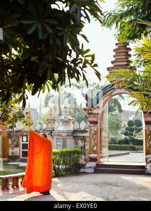 Un giovane monaco fissa la sua tunica di Wat Si Muang, Vientiane, Laos, P.D.R. Foto Stock