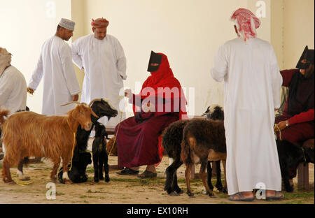 Bedu (Beduino) persone che acquistano e vendono capre al mercato degli animali in Sinaw, Oman Foto Stock