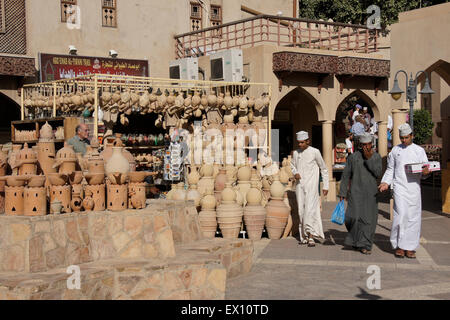 Omani uomini con pentole di creta per la vendita nel mercato, Nizwa, Sultanato di Oman Foto Stock