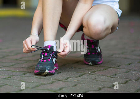 Giovane donna è la legatura dei lacci prima dell'esecuzione. Close-up, acceso, uno stile di vita sano. Foto Stock