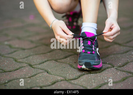 Close-up, ragazza è la legatura i lacci delle scarpe sportive prima dell'esecuzione. Foto Stock