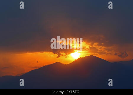 Sun spiata attraverso dissipare nuvole temporalesche al tramonto sulle Alpi Foto Stock