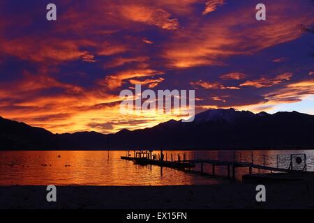 Sun spiata attraverso dissipare nuvole temporalesche riflessa in un lago al tramonto sulle Alpi Foto Stock