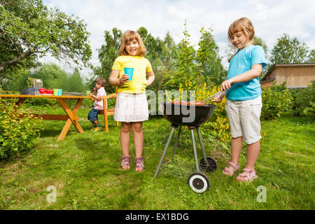 Due ragazze vicino grill rendendo il barbecue nel giardino Foto Stock