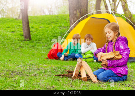 Felice ragazza con la legna per il falò in campeggio Foto Stock