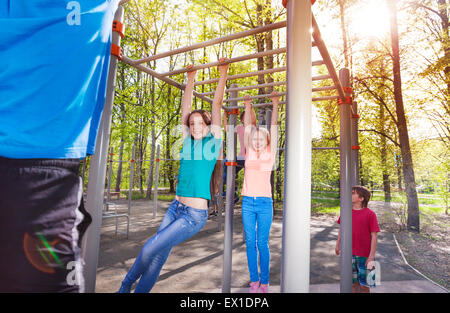 Appendere teens sulla barra orizzontale presso gli sport di terra Foto Stock