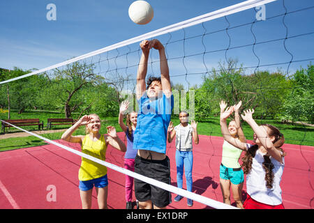 Gli adolescenti sono tutte con le braccia in alto giocare a pallavolo Foto Stock