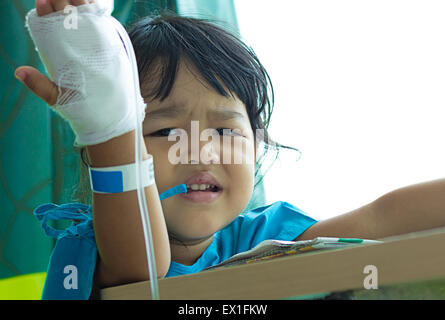 Malattia bambini asiatici gridare, seduto su una sedia in ospedale, soluzione salina per via intravenosa (IV) a portata di mano Foto Stock