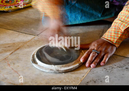 Donna birmano facendo thanaka crema è effettuata macinando la corteccia, legno, o le radici di un albero thanaka con una piccola quantità di acqua su un Foto Stock