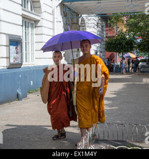 Due monaci buddisti in tipici abiti dello zafferano camminare sotto un ombrellone sul trefolo a Yangon Myanmar Foto Stock